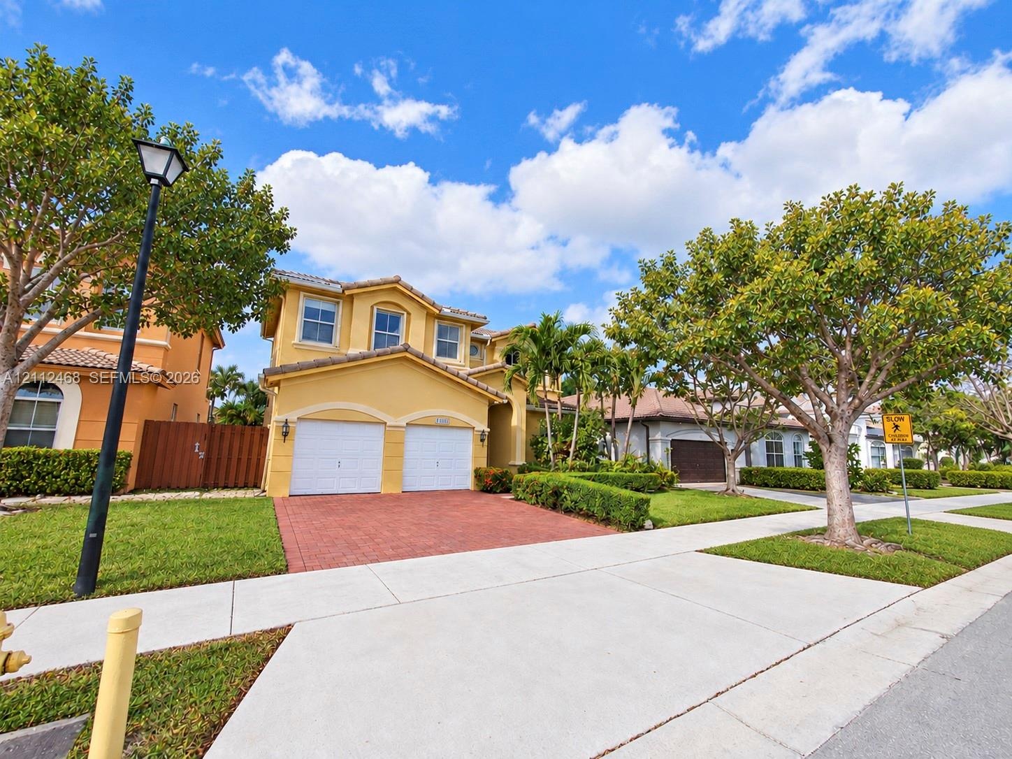 Stucco exterior residence featuring a two-car garage, paver driveway, and tiled roof