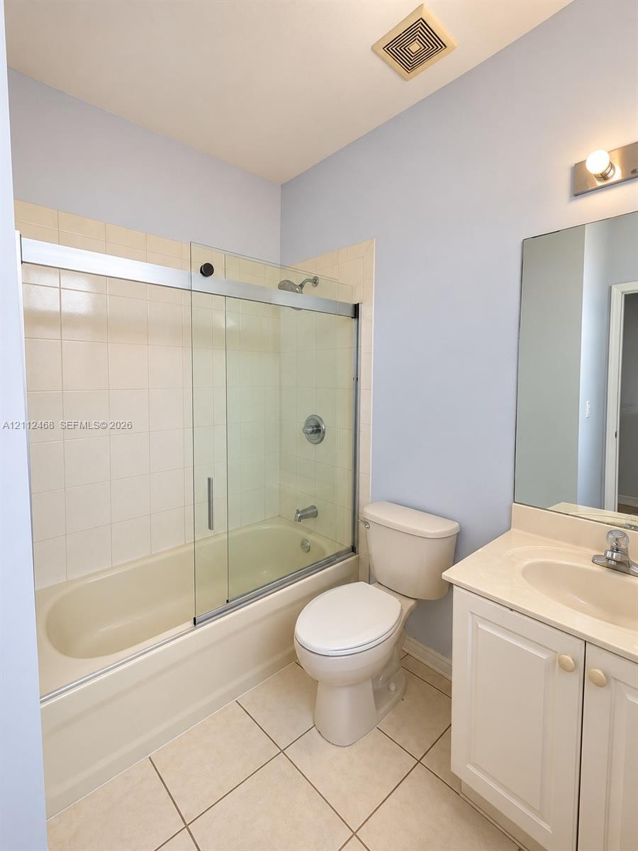 Bathroom featuring a tub-shower combination with glass sliding doors, ceramic tile shower surround, vanity with an integrated sink, and large wall-mou
