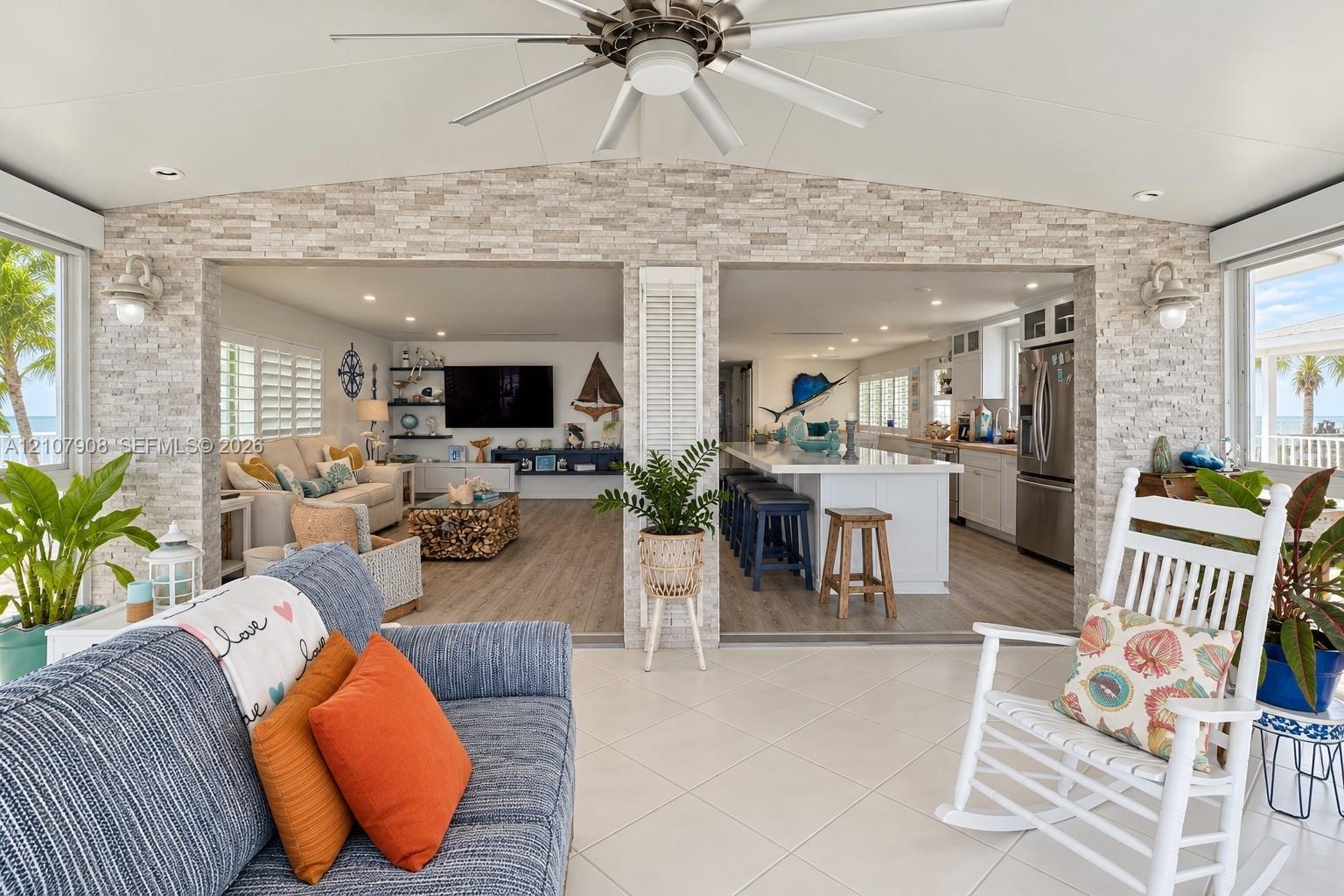 Covered patio featuring a stacked stone accent wall, recessed lighting, a ceiling fan, and large-format tile flooring
