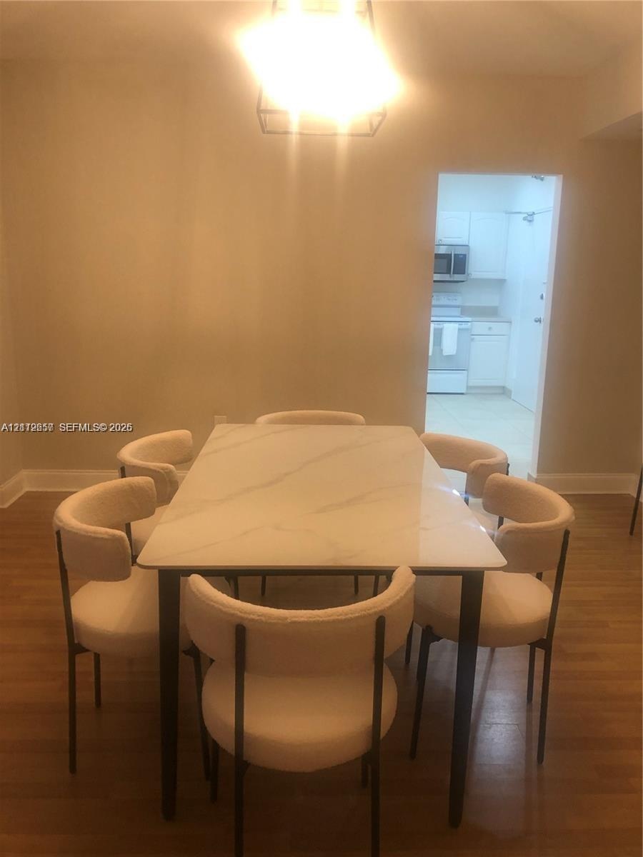 Dining area featuring wood-finish flooring and a geometric pendant light fixture
