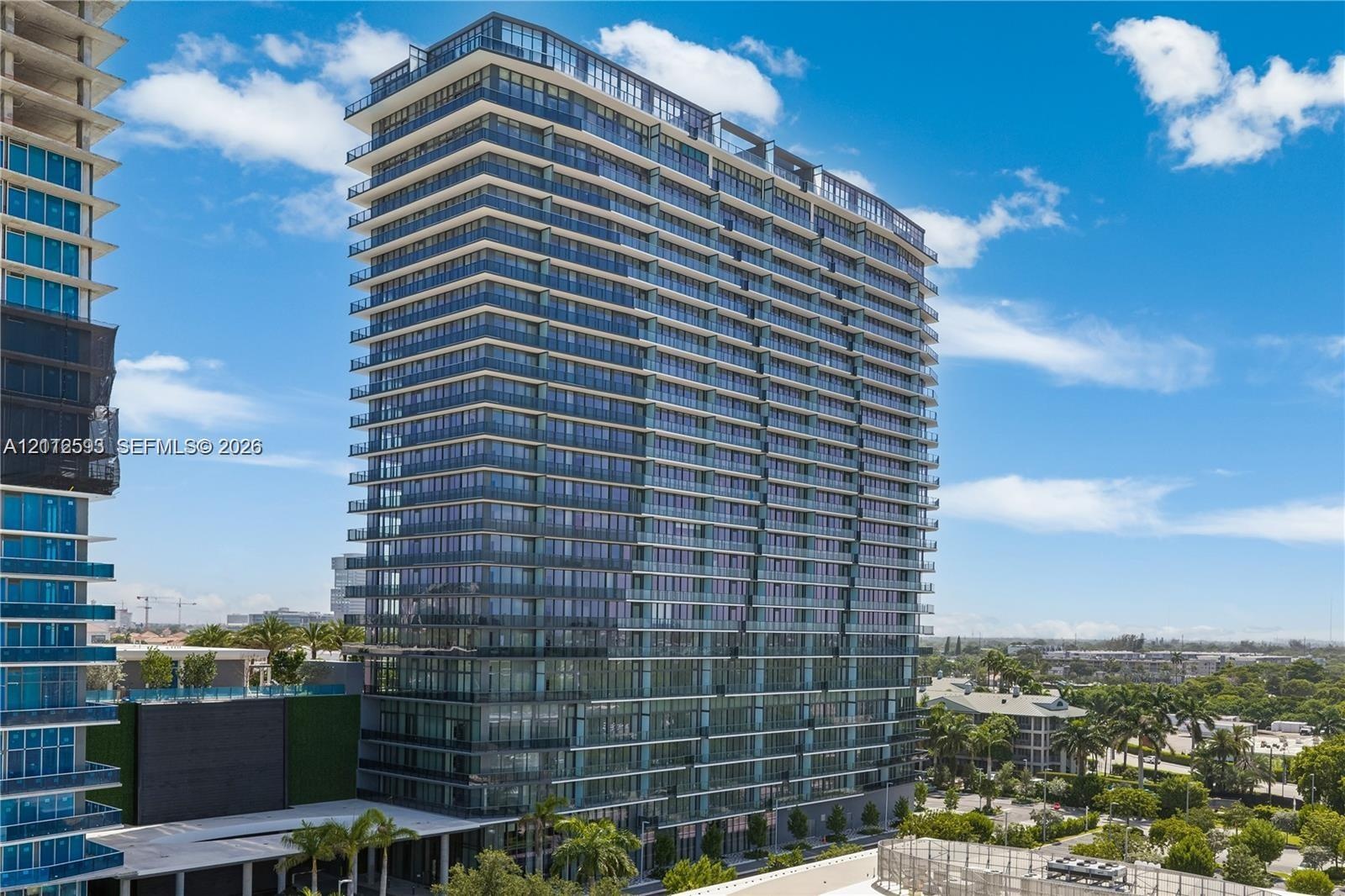 High-rise residential tower featuring a glass facade, floor-to-ceiling windows, and private exterior balconies on every level