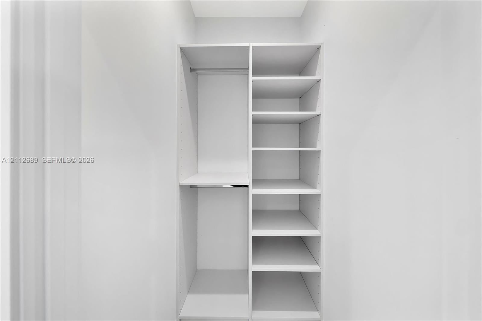 Built-in white storage system featuring dual hanging rods and adjustable open shelving