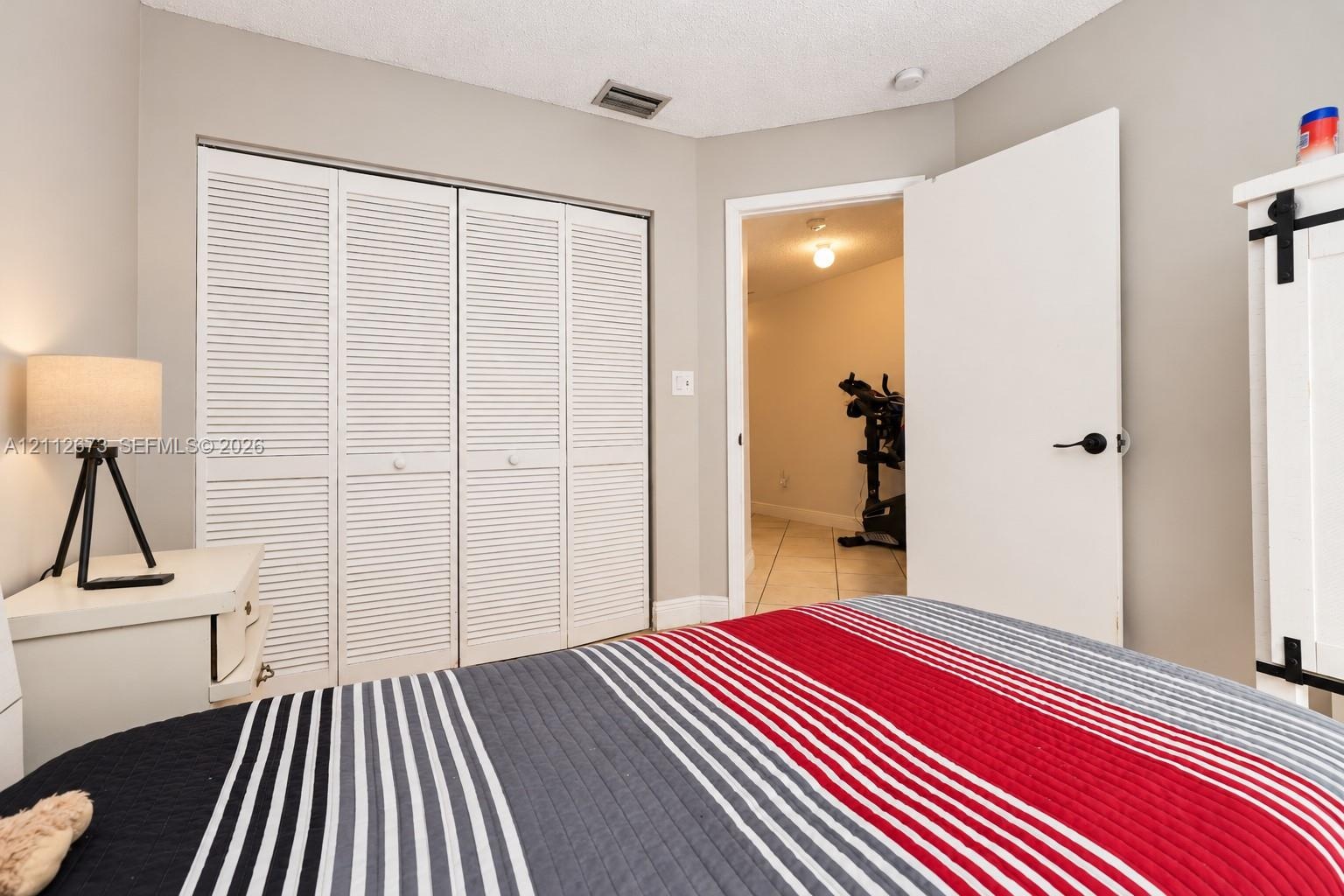 Room featuring four-panel louvered closet doors and a solid core interior door with matte black hardware