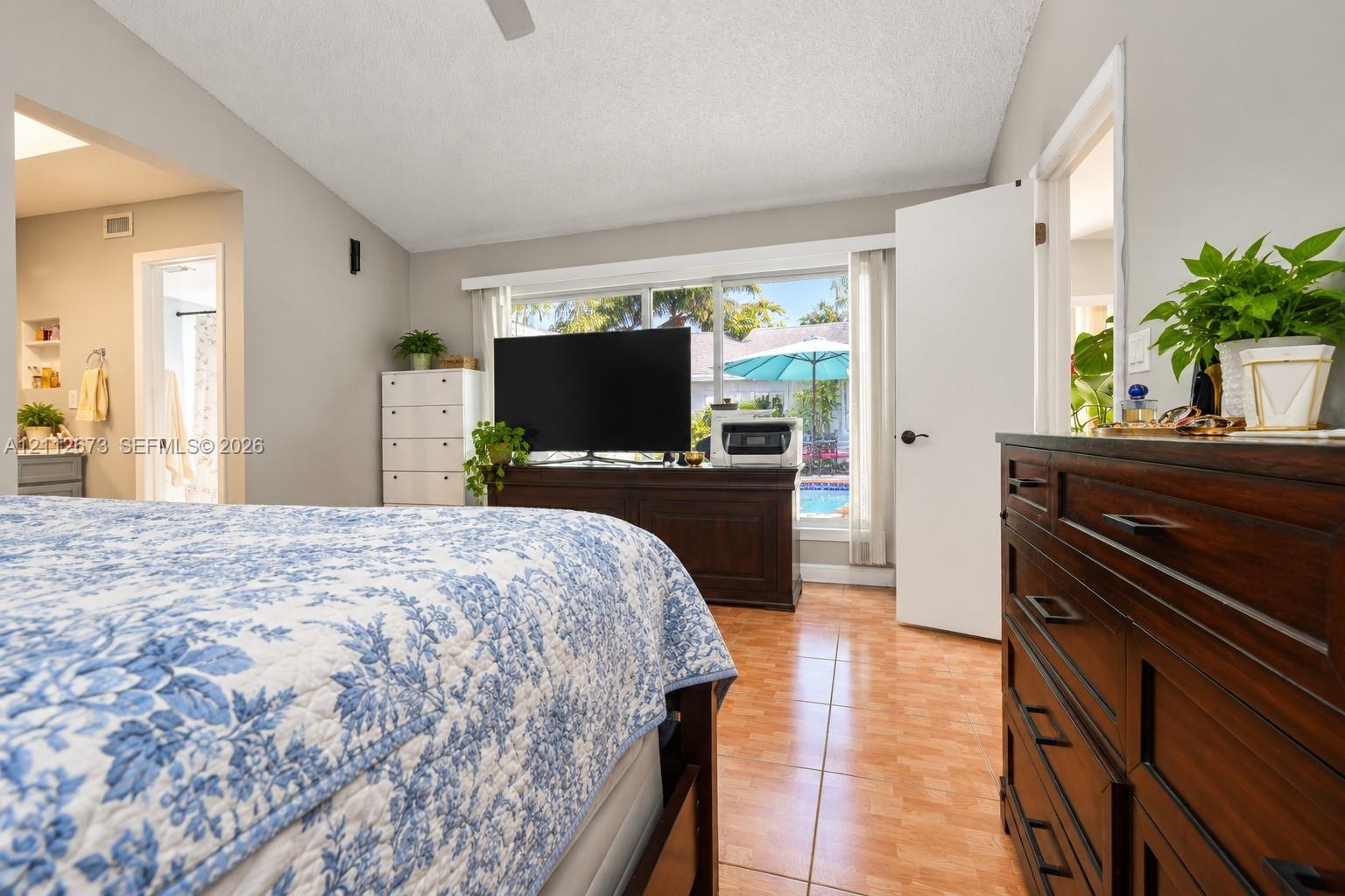 Vaulted ceiling with a central fan, ceramic tile flooring, and a large horizontal window providing exterior visibility