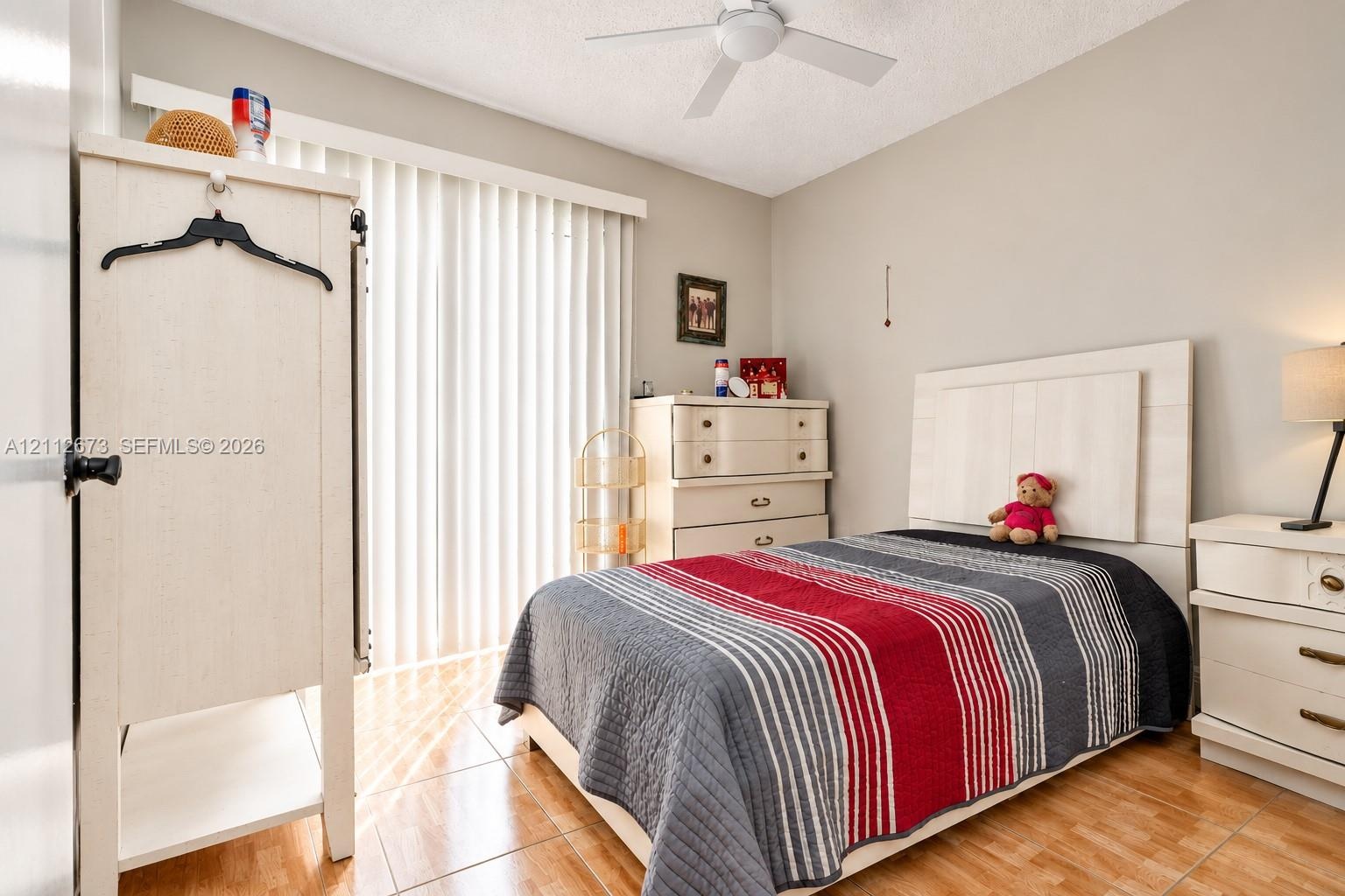 Ceramic tile flooring, white ceiling fan with integrated lighting, and vertical window blinds