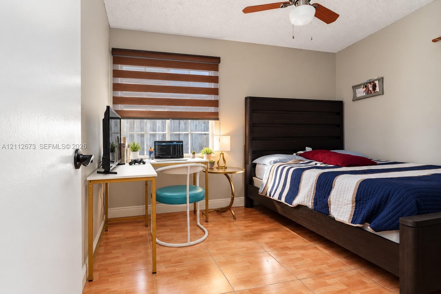 Room featuring wood-finish tile flooring, a dual-tone fabric window shade, and a ceiling-mounted light fixture with a fan