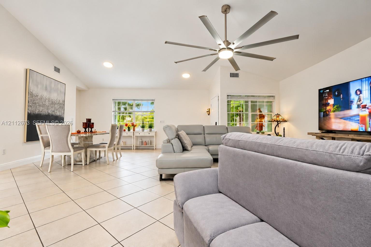 Vaulted ceilings featuring a multi-blade brushed metal ceiling fan and recessed lighting, finished with light-toned ceramic tile flooring and multi-pa