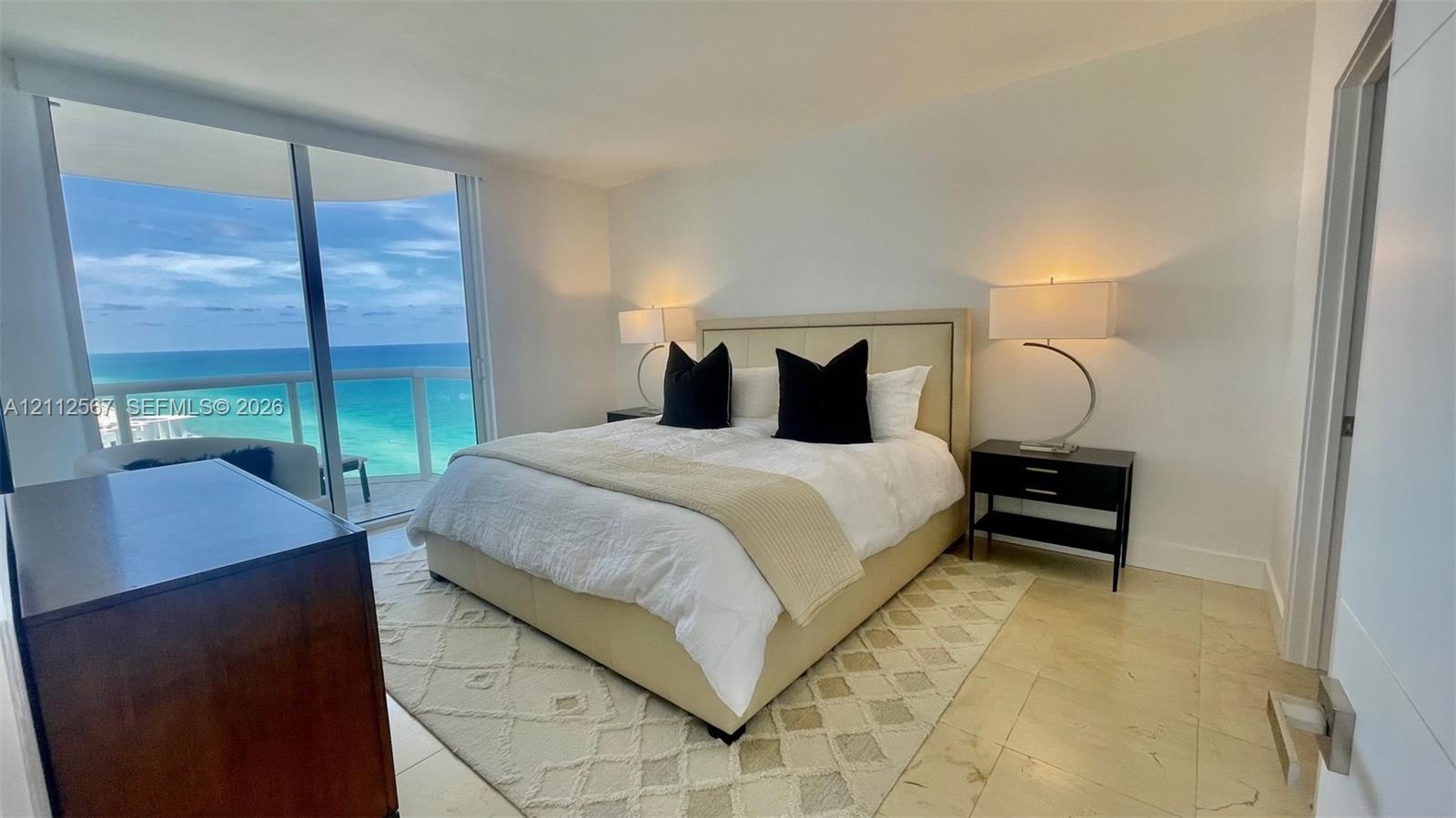 Full-height glass sliding doors, polished stone flooring, and expansive ocean horizon