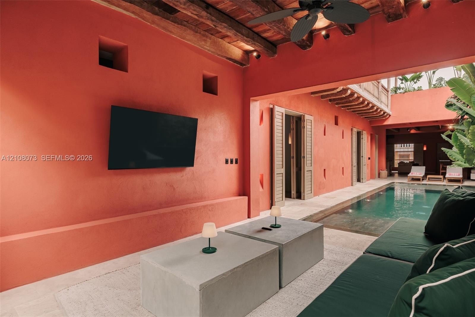 Open-air courtyard featuring a private pool, exposed timber ceiling beams, textured terracotta-toned walls, and stone-finish flooring
