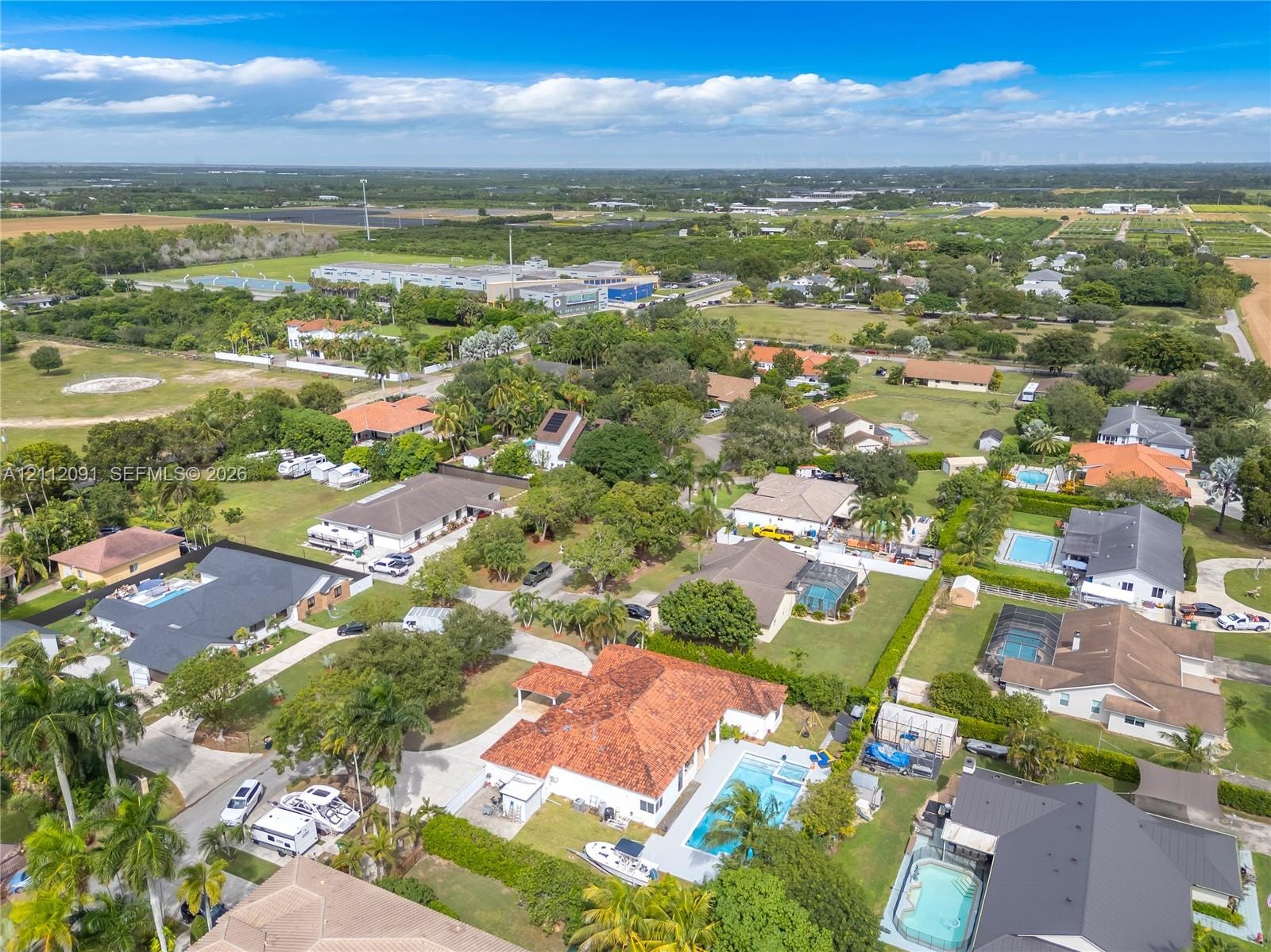 Aerial perspective featuring a residence with a clay tile roof, concrete driveway, and in-ground swimming pool