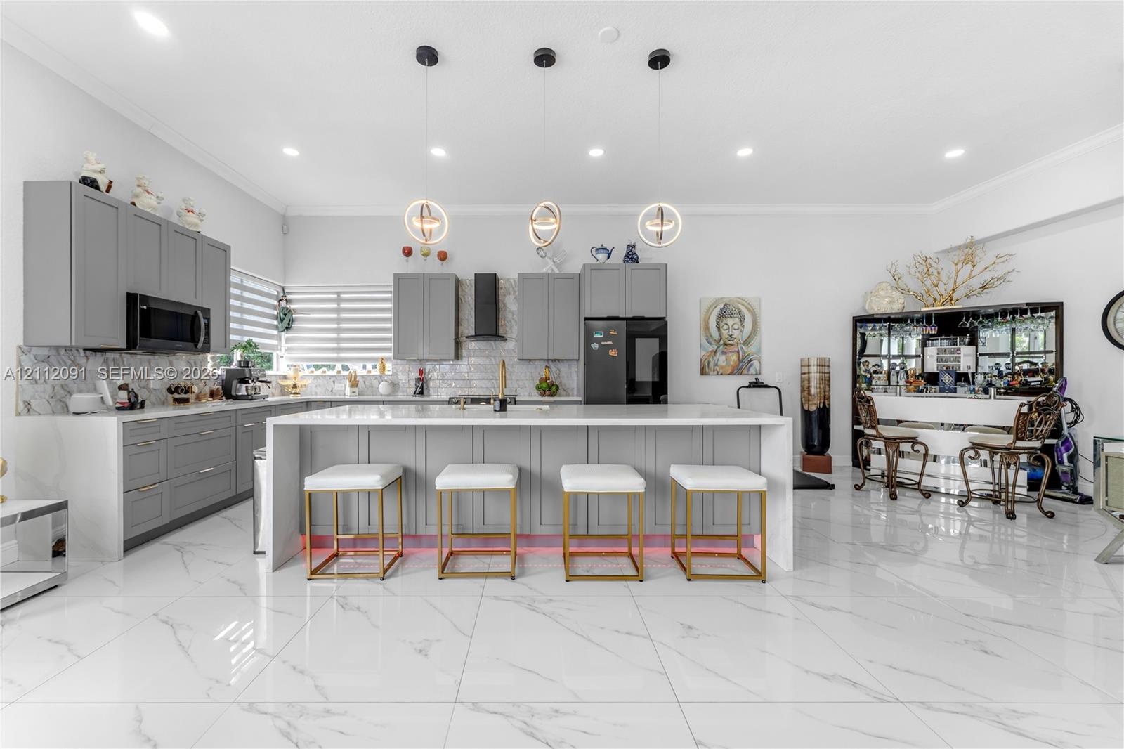 Kitchen featuring light-gray shaker-style cabinetry, quartz countertops, a stone-tile backsplash, polished large-format tile flooring, and three conte