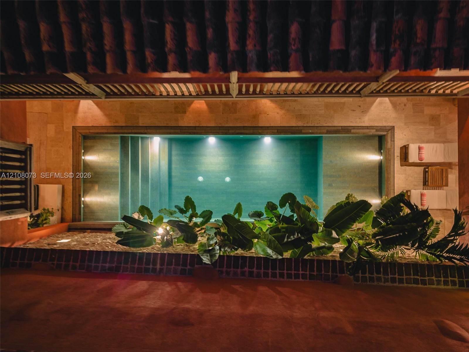 Indoor swimming pool with tiered entry steps, natural stone wall cladding, built-in recessed lighting, and integrated planters
