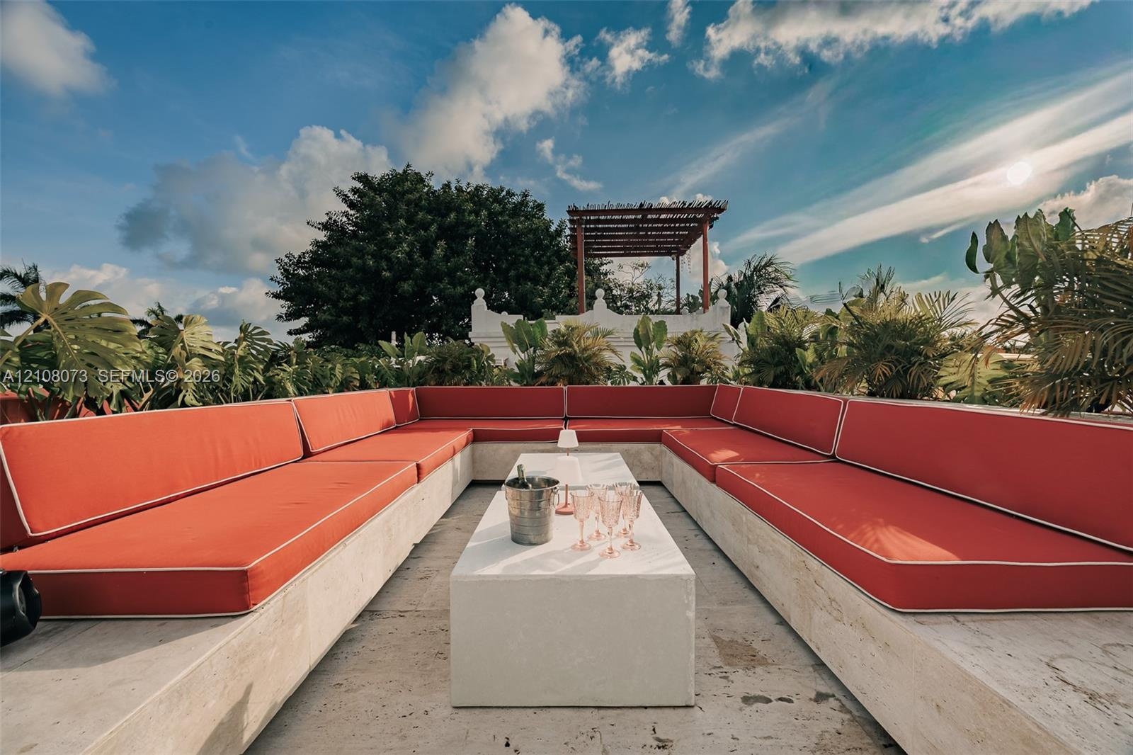 Rooftop terrace featuring built-in stone bench seating, a centered stone-finish table, and a wooden pergola structure