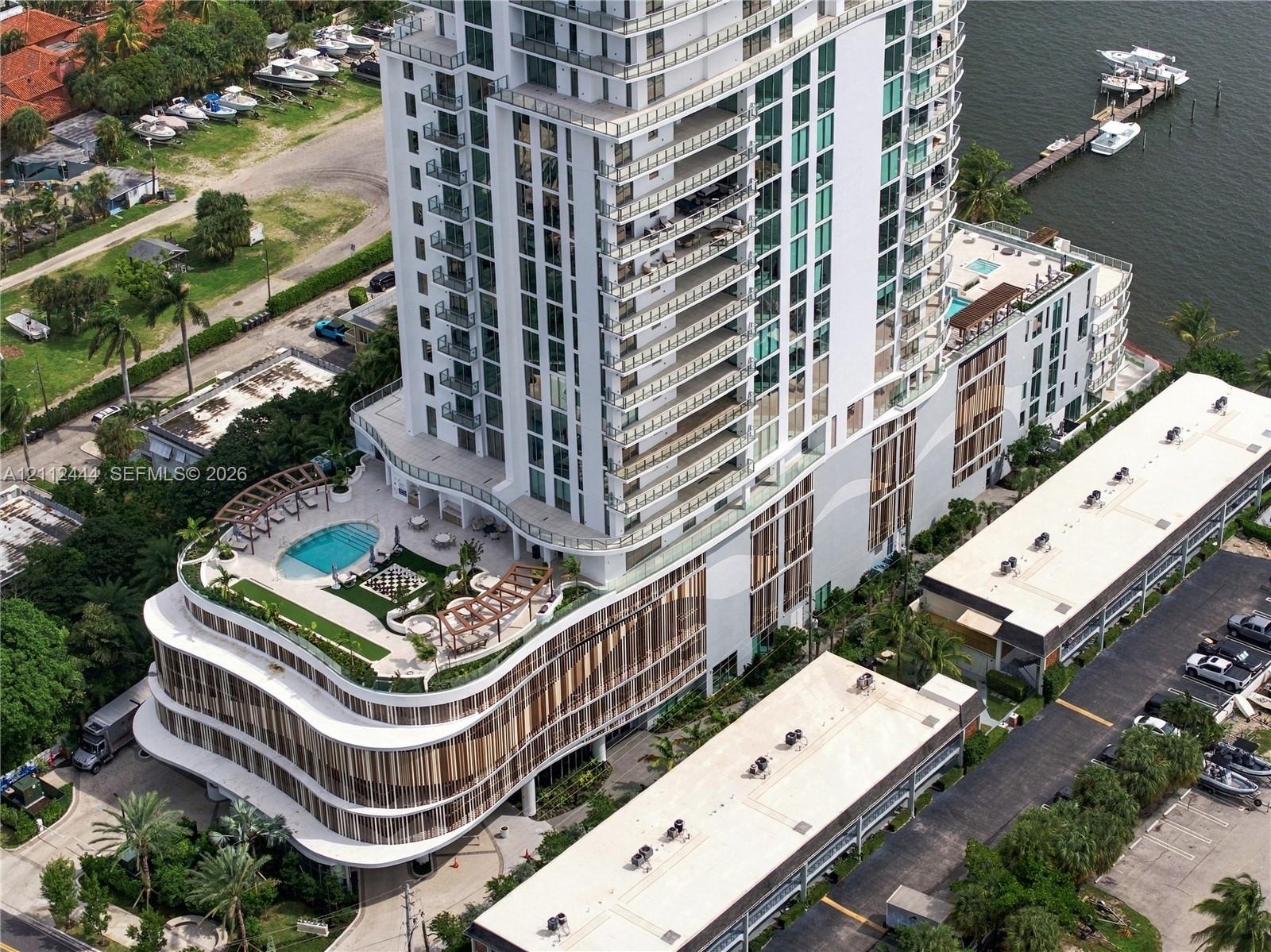 High-rise residential tower featuring a multi-level structure, wraparound balconies, an elevated swimming pool with a sprawling sun deck, and integrat