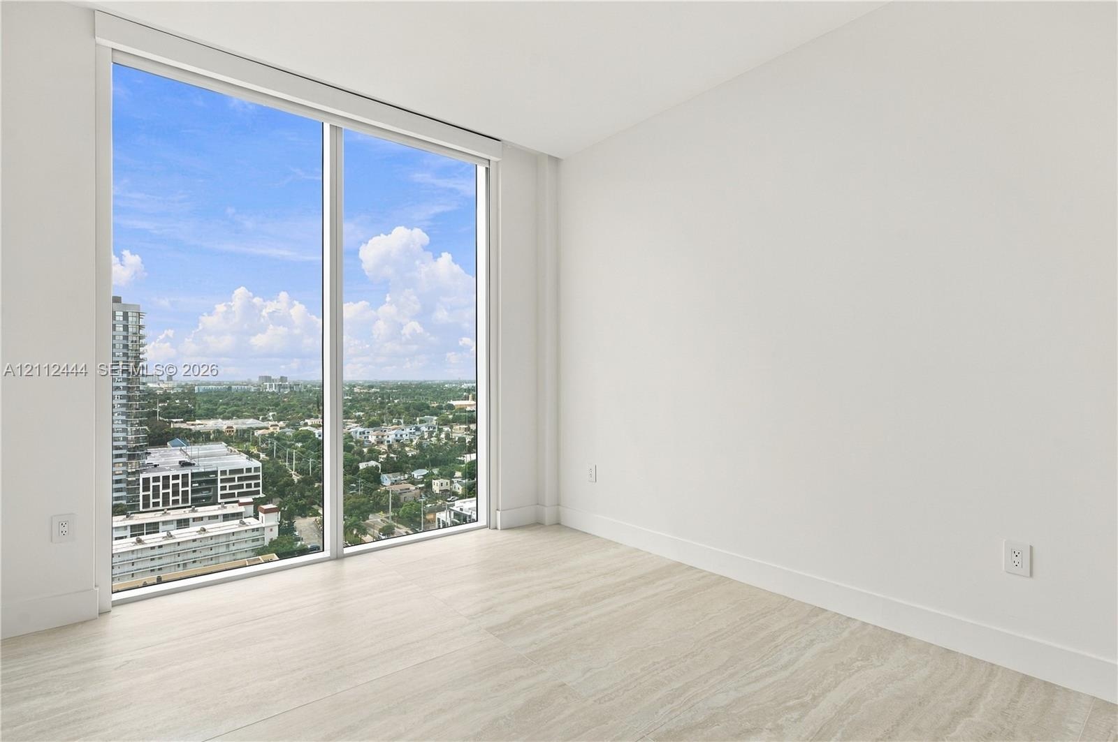 Floor-to-ceiling windows, neutral interior walls, and stone-finish flooring