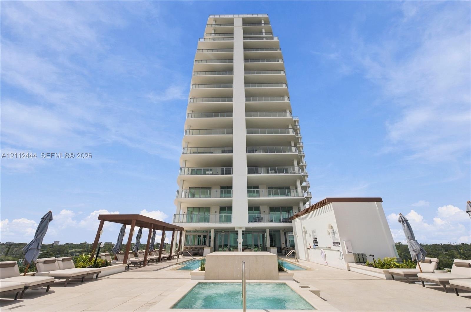 High-rise building exterior featuring tiered balconies with metal railings, elevated terrace level, tiled sundeck, built-in swimming pool, and custom 