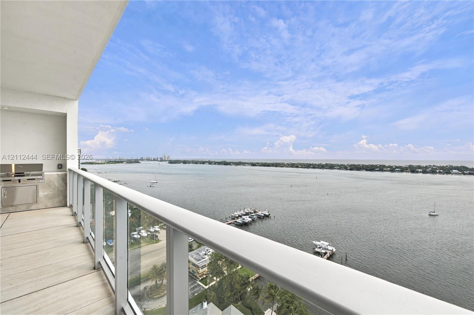 Covered balcony featuring a glass railing, tiled flooring, and a built-in stainless steel outdoor kitchen station