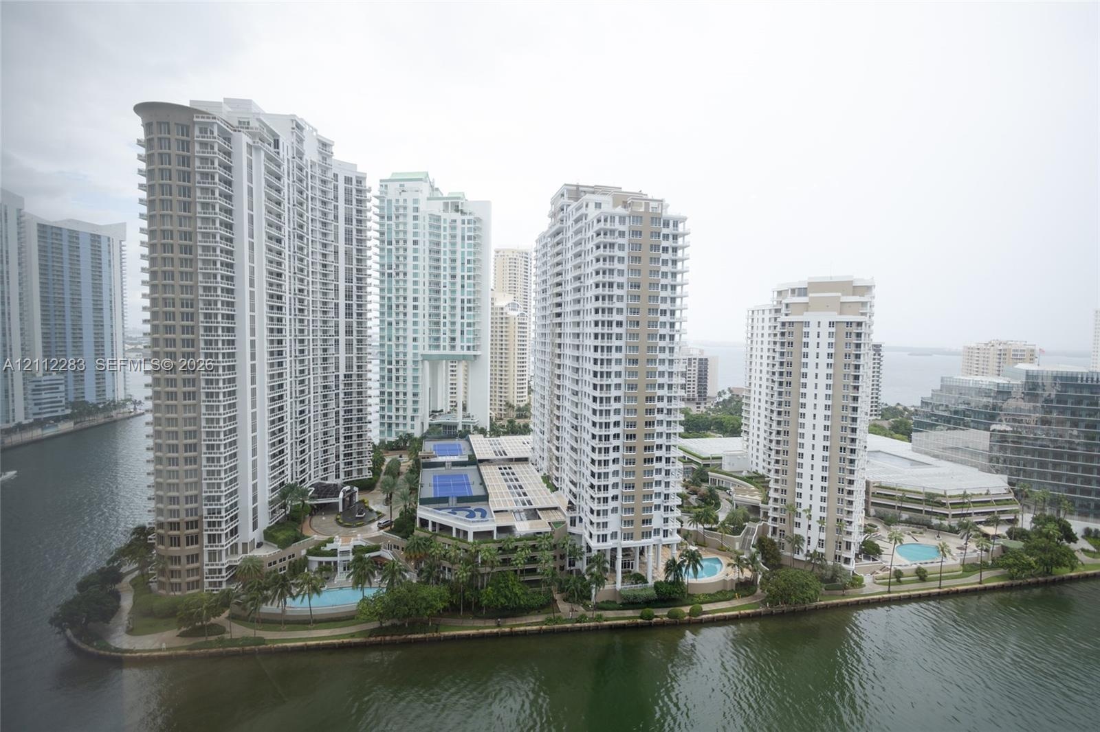 High-rise residential complex featuring waterfront positioning, tennis courts, multiple swimming pools, and landscaped grounds