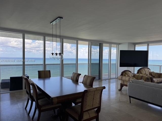 Floor-to-ceiling glass panel windows, polished stone flooring, three-globe pendant lighting, and an expansive balcony