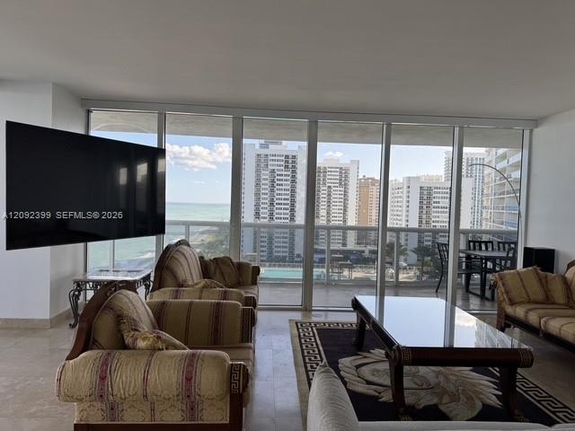 Floor-to-ceiling windows, polished stone flooring, and a glass-paneled balcony overlooking the coastal skyline