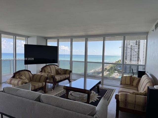 Floor-to-ceiling windows, wrap-around balcony access, stone flooring, and expansive ocean frontage
