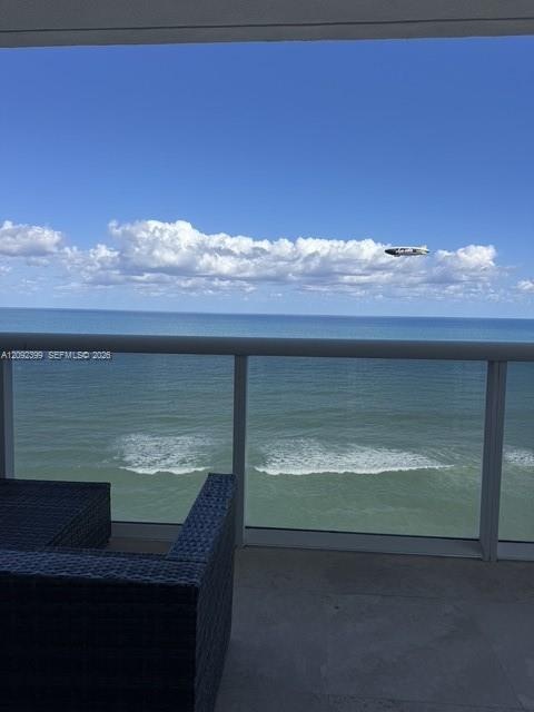 Covered balcony featuring a glass panel railing and concrete flooring