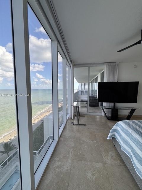 Floor-to-ceiling windows featuring panoramic coastal scenery, large-format tile flooring, and a private balcony with glass railing