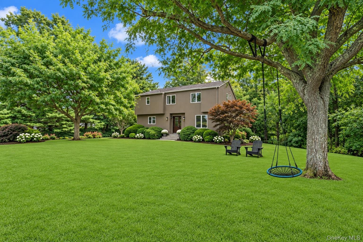 Expansive, manicured lawn featuring mature trees and established perimeter landscaping