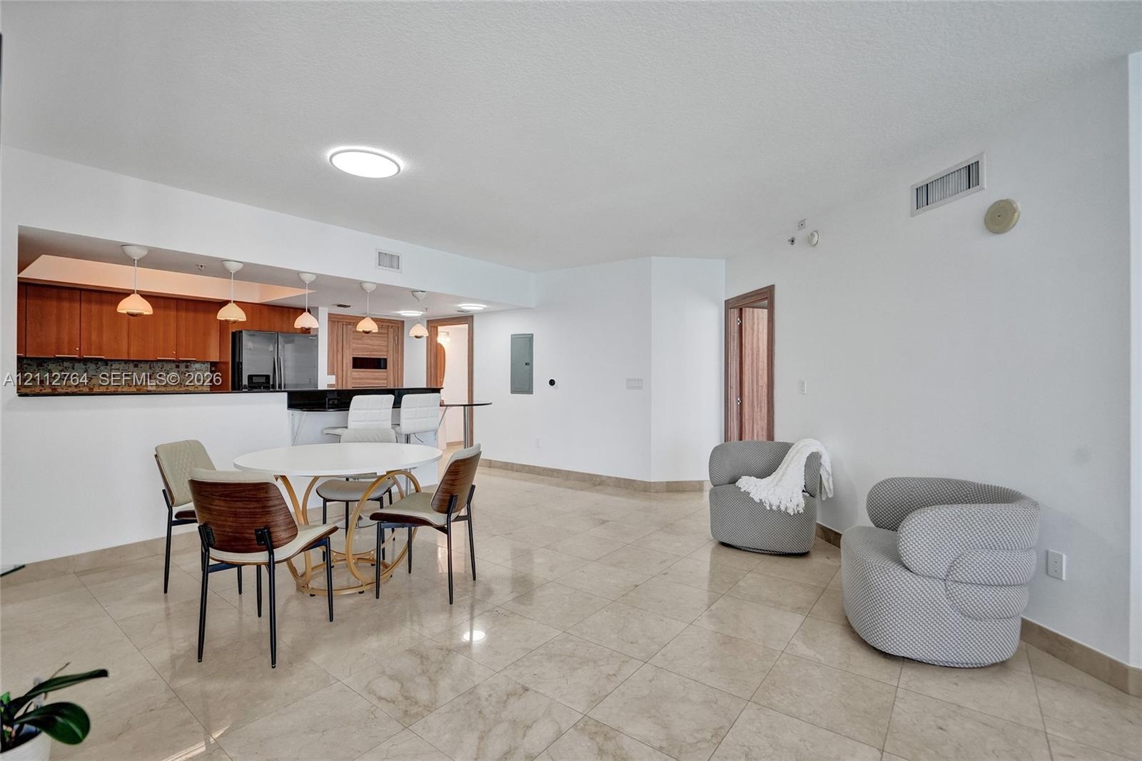 Open-concept area featuring tile flooring, kitchen with wood-finish cabinetry, breakfast bar, and recessed lighting
