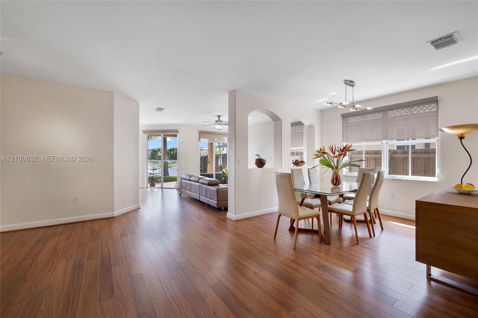 Wood-finish flooring, architectural arched wall niches, sliding glass patio doors, and multi-light linear ceiling fixture