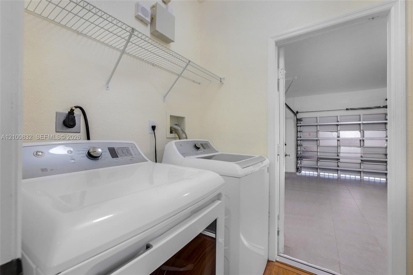 Laundry area featuring overhead wire shelving and wood-finish flooring