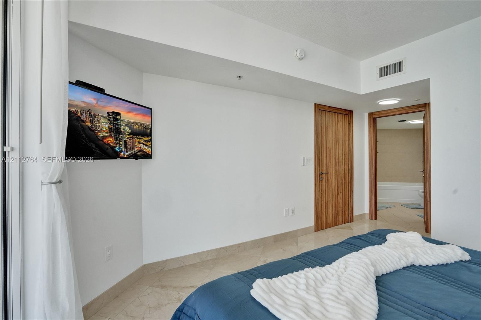 Light-toned tile flooring, solid wood-finish door, and recessed lighting