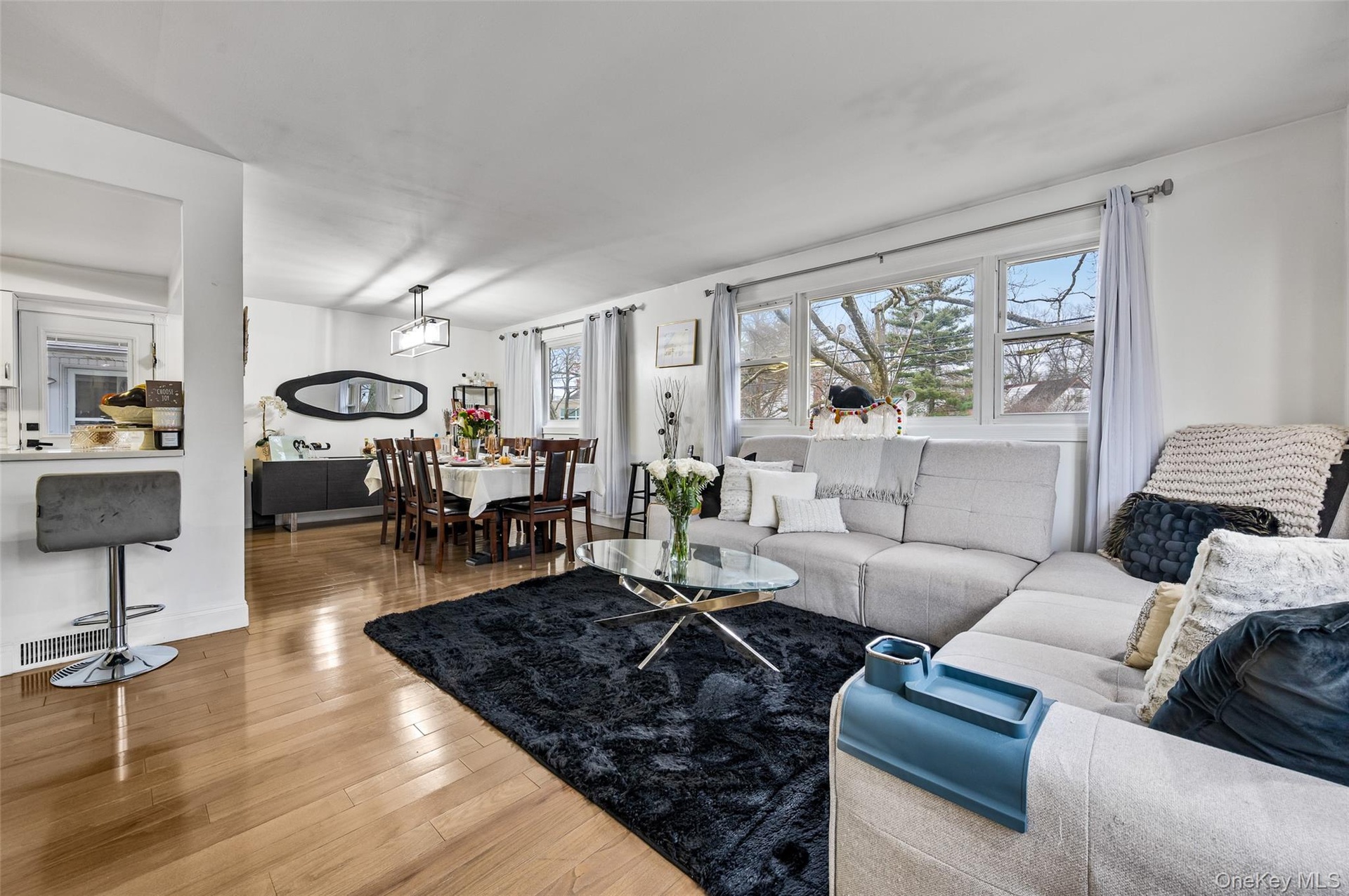 Open-concept living and dining area featuring wood-finish flooring, recessed lighting, expansive windows, and a built-in breakfast bar