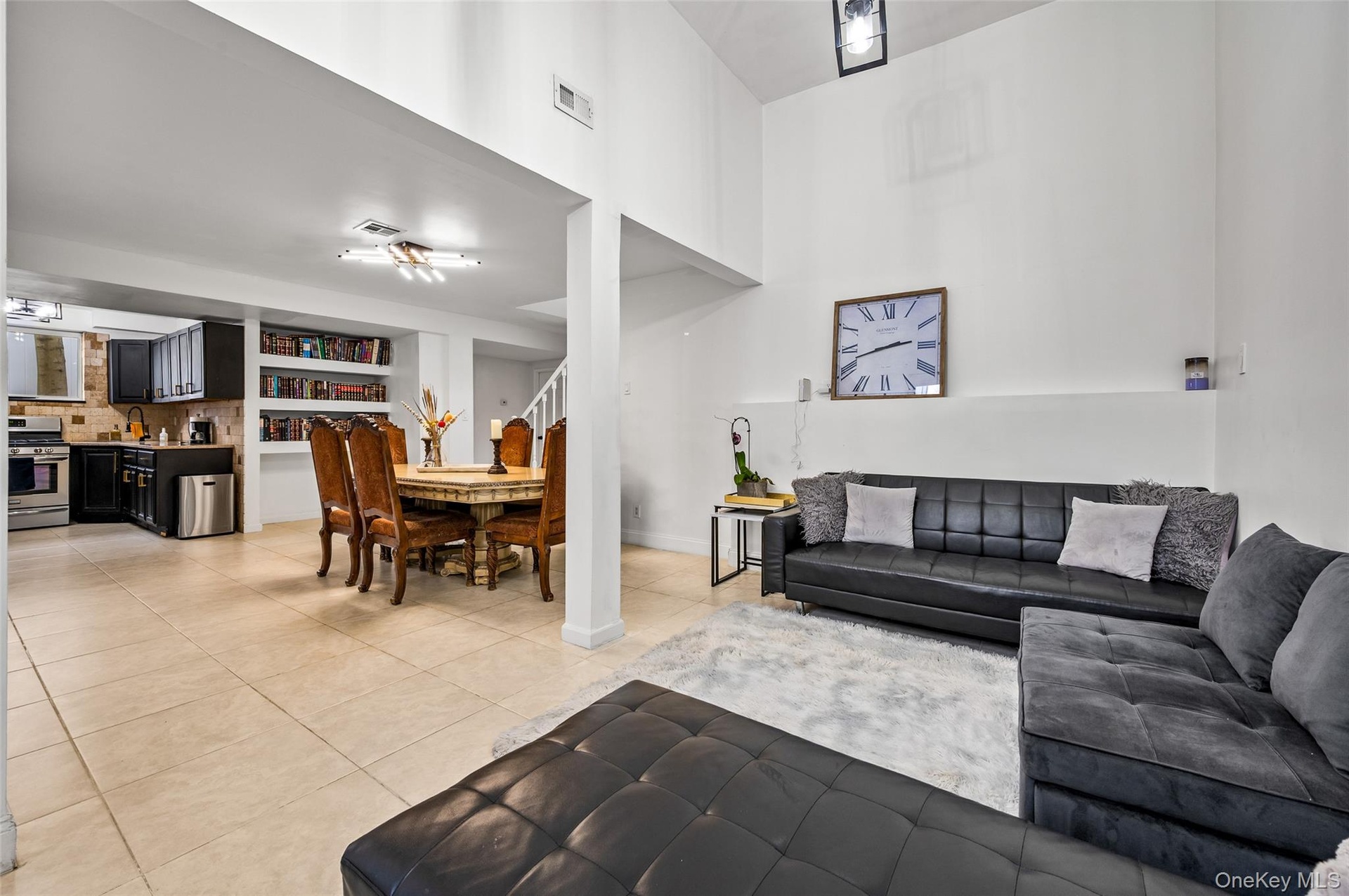 Vaulted ceilings, large-format tile flooring, built-in shelving, multi-directional recessed lighting, and a dark-finish kitchen cabinetry package