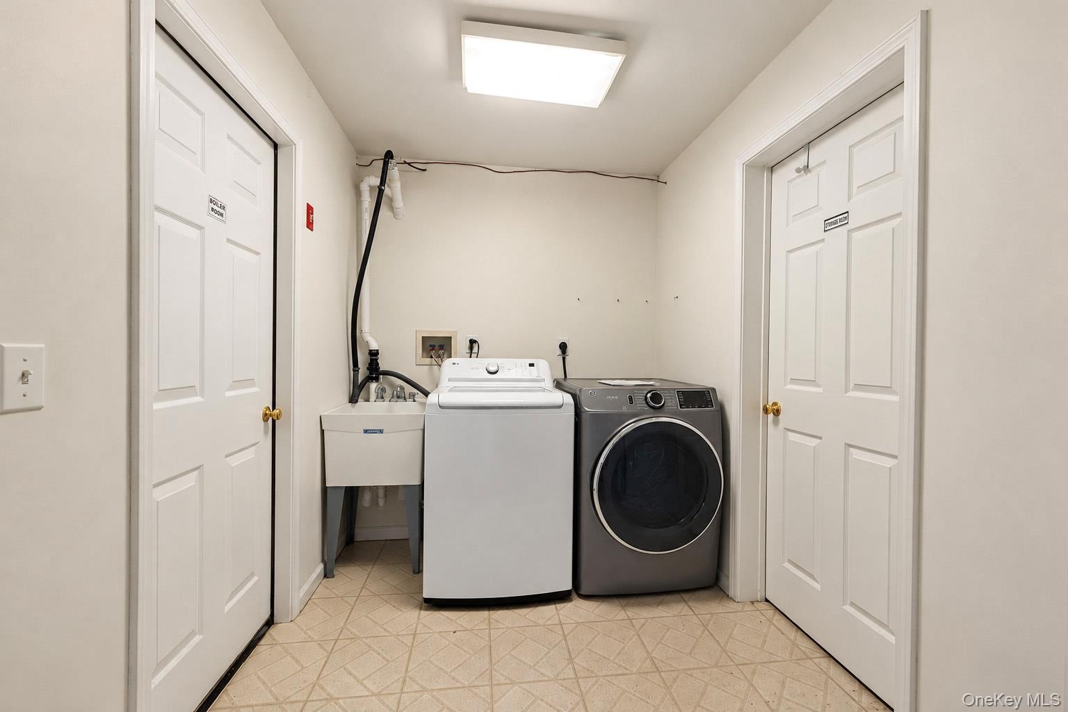 Laundry area featuring a utility sink, built-in appliance hookups, overhead lighting, and two six-panel doors set over tiled flooring