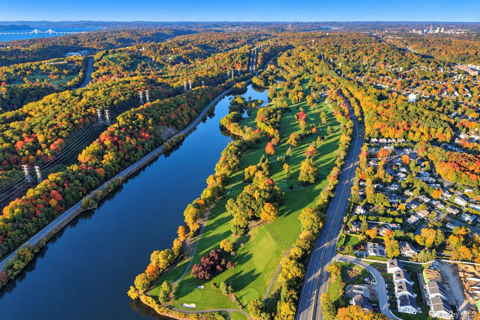 Aerial perspective of a golf course featuring manicured fairways, integrated water features, and expansive mature greenery