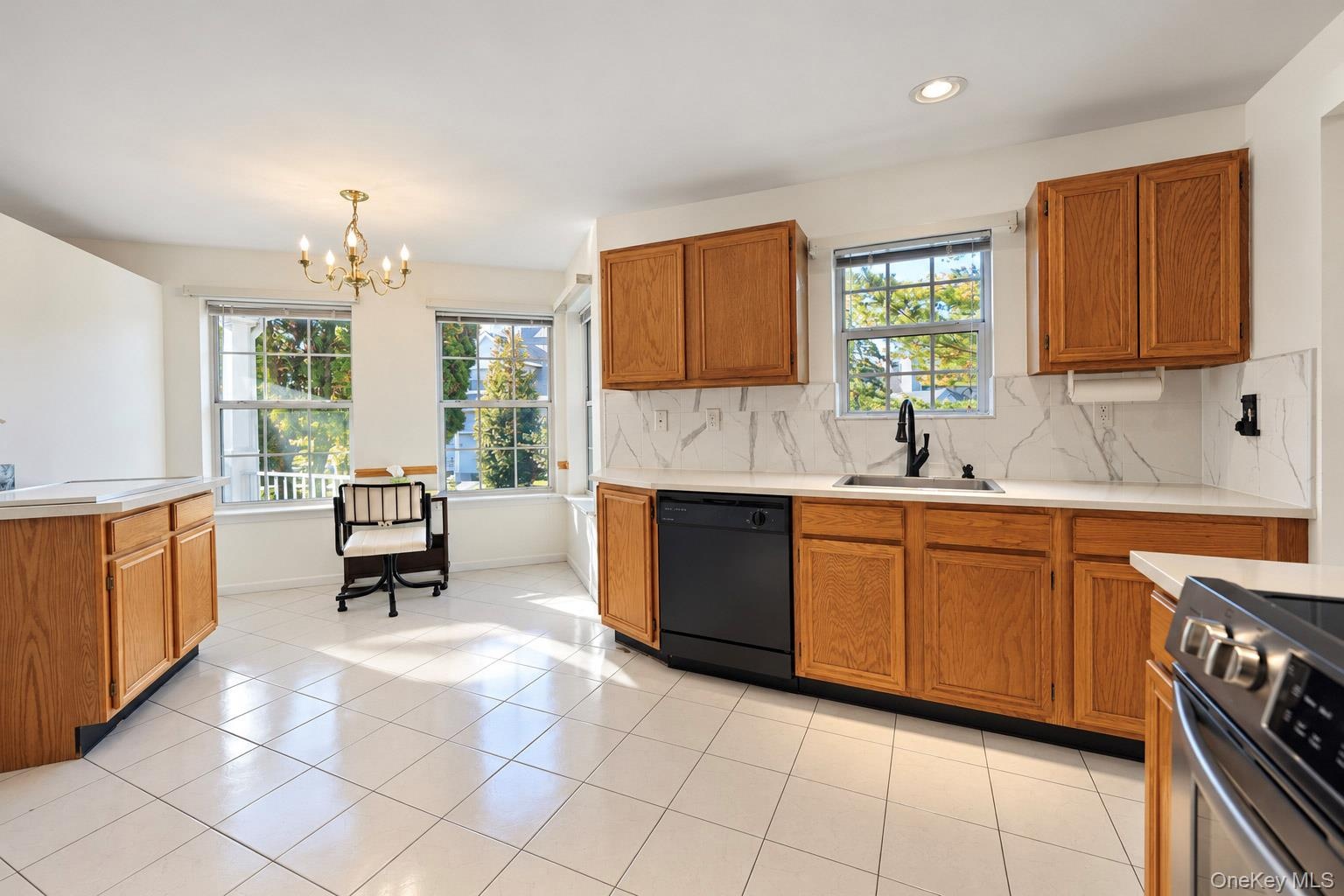 Kitchen featuring white tile flooring, wood cabinetry, stone-style backsplash, integrated matte black faucet, and recessed lighting