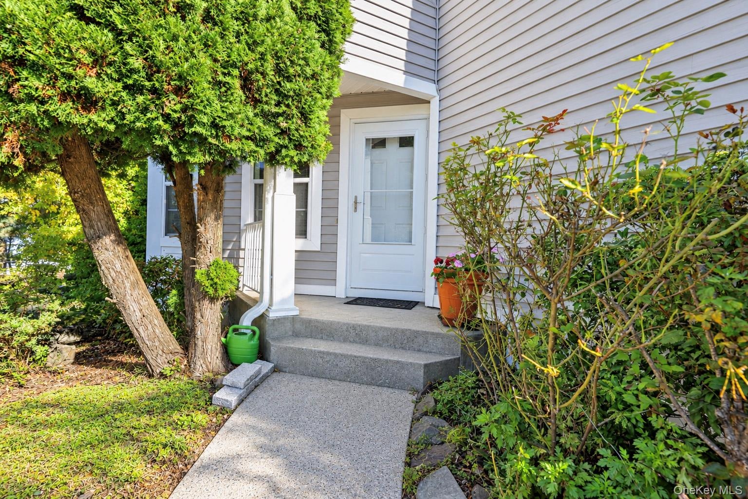 Exterior entryway featuring horizontal siding, a concrete staircase, and a white-framed glass-panel door