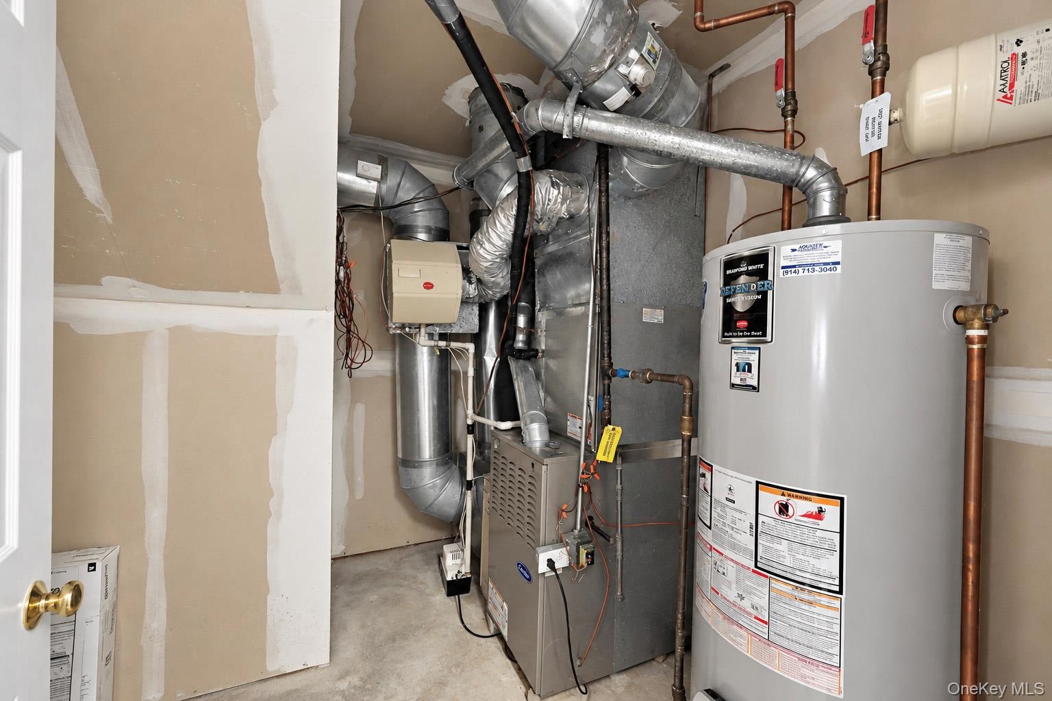 Mechanical utility closet housing a high-efficiency furnace, metal ductwork, and a vertical water heater with copper piping