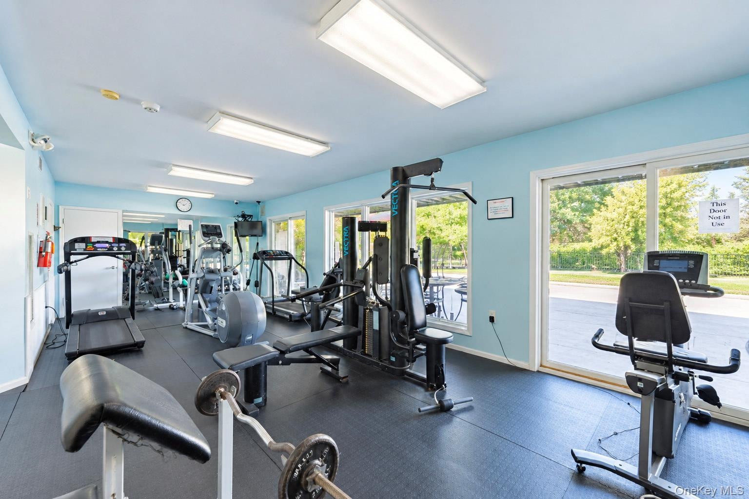 Fitness center featuring rubber flooring, recessed fluorescent lighting, and large sliding glass doors
