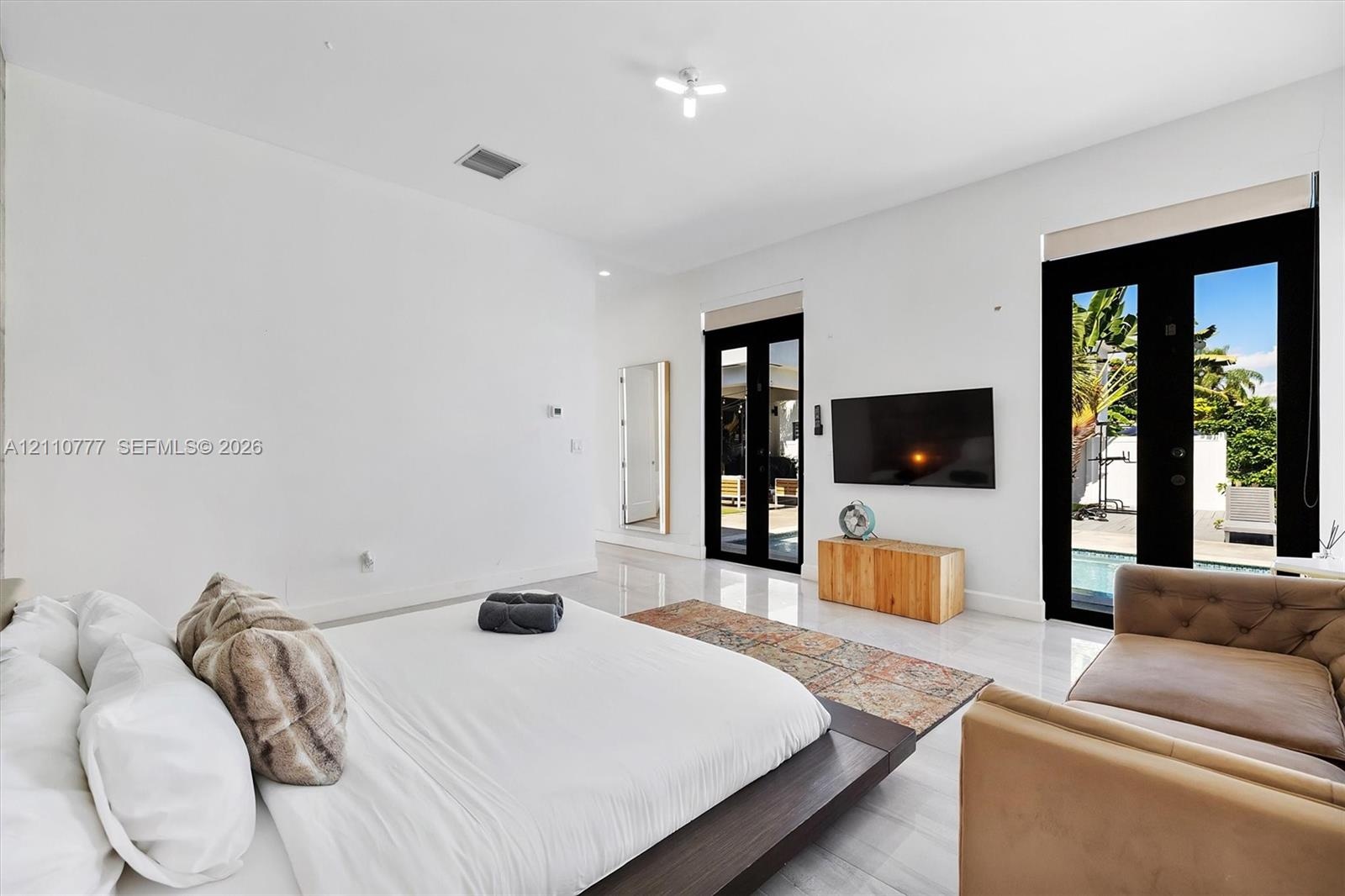 Polished large-format tile flooring, high ceilings, and double glass-paneled exterior doors with black frames