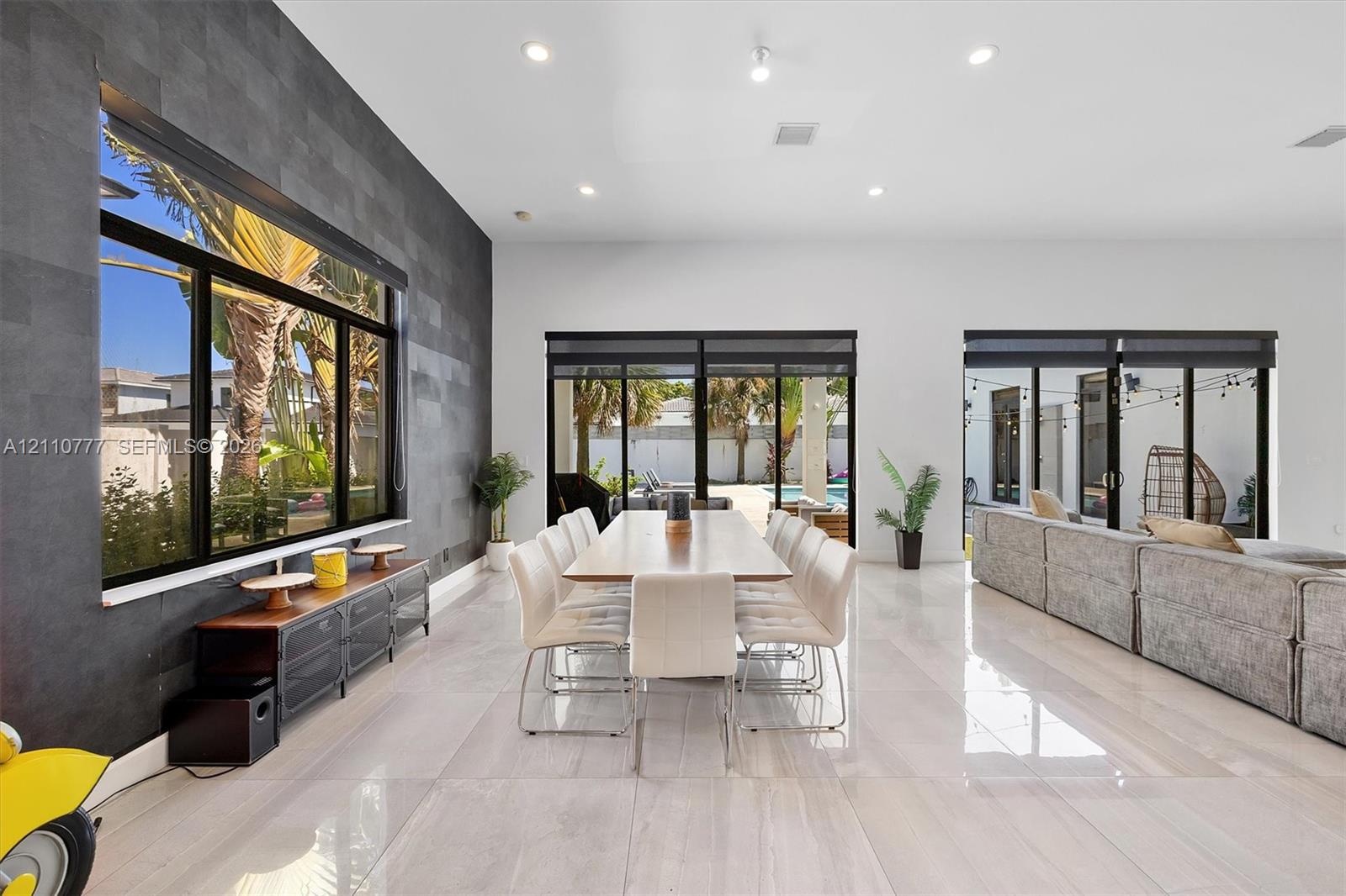 Spacious interior featuring large-format tile flooring, a charcoal-toned textured accent wall, recessed lighting, and multiple sliding glass door syst