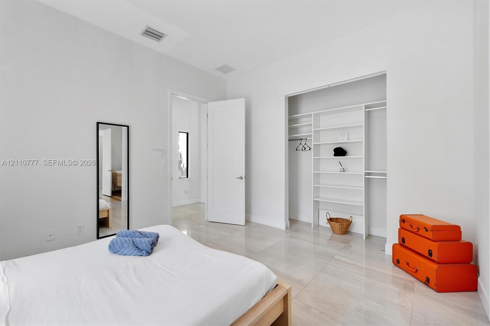 Interior space featuring light-toned tile flooring, high ceilings, and a built-in walk-in closet system with shelving