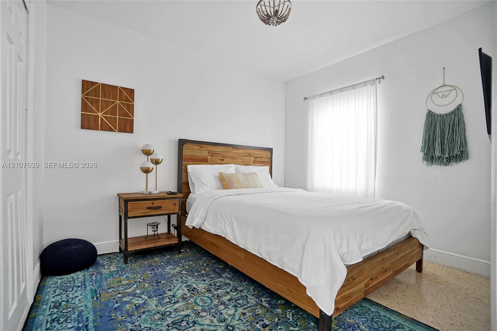 Neutral-toned walls, ceiling-mounted decorative light fixture, single-panel door, and window with rod-mounted drapery