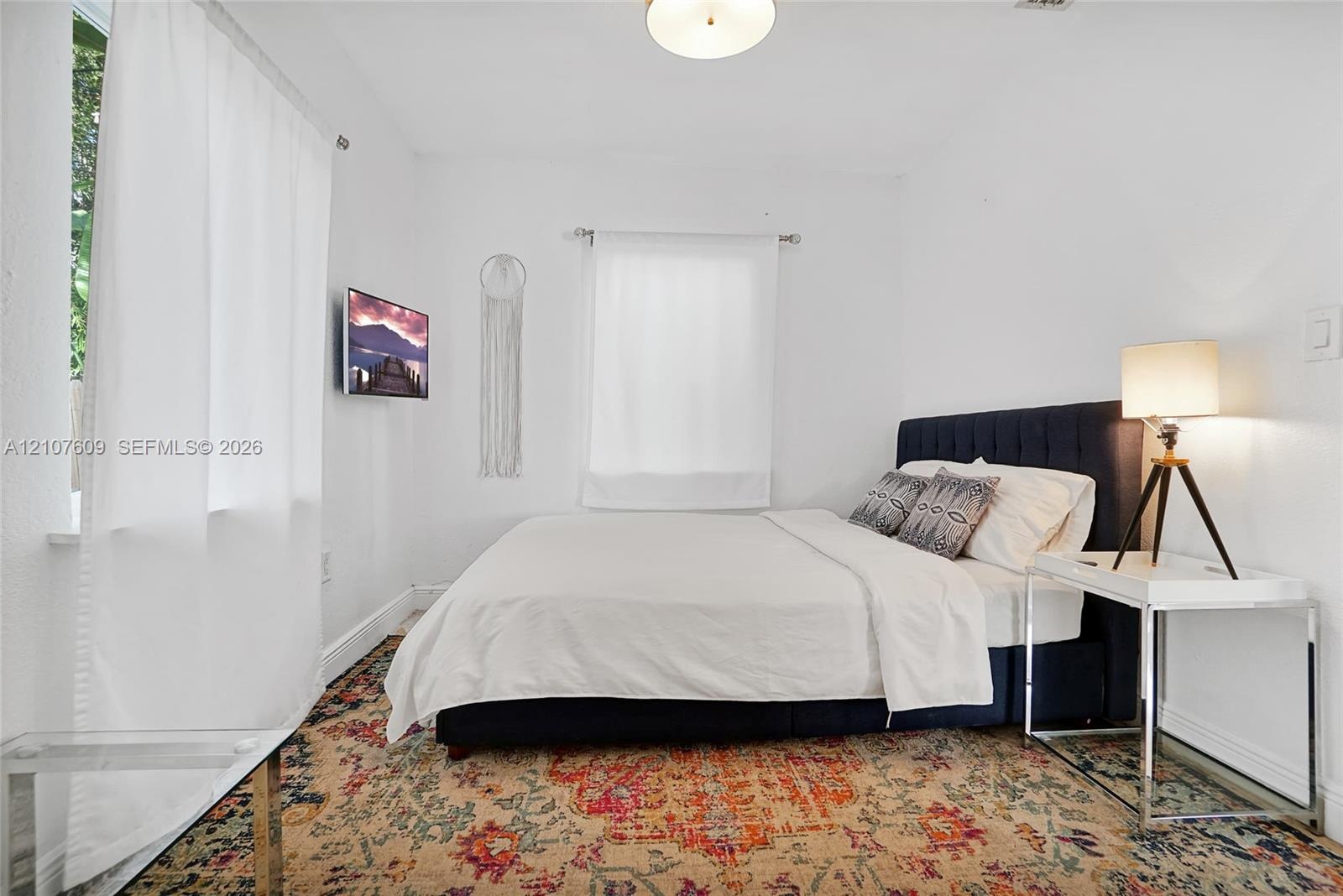 Neutral interior space featuring white walls, two double-hung windows, and a flush-mount ceiling light fixture