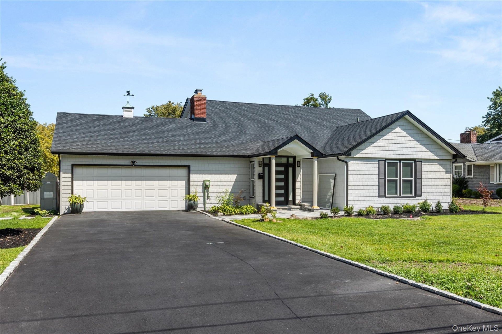 View of front of home with driveway, a front lawn, a garage, a shingled roof, and a chimney