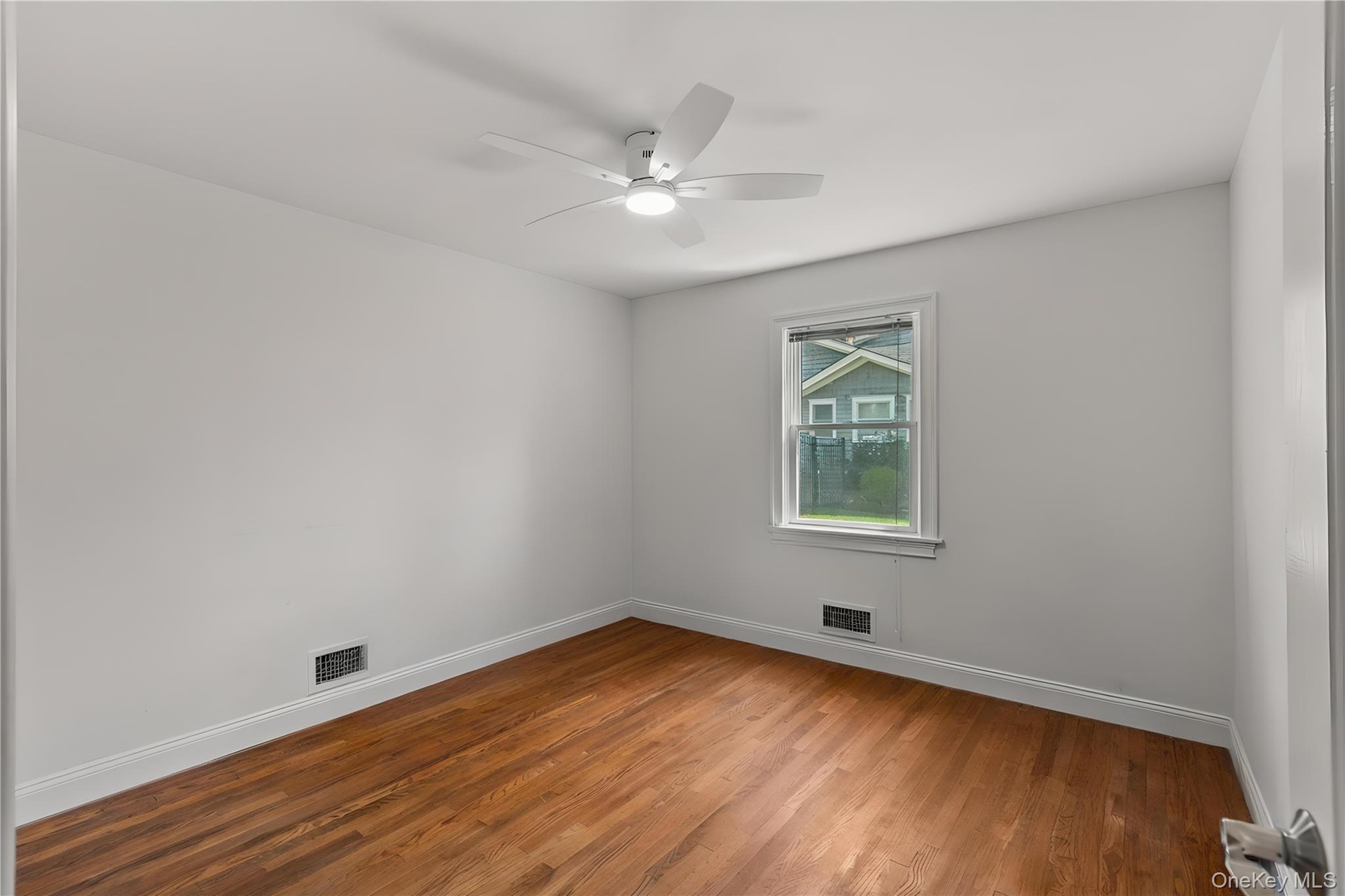 Empty room with wood finished floors and a ceiling fan