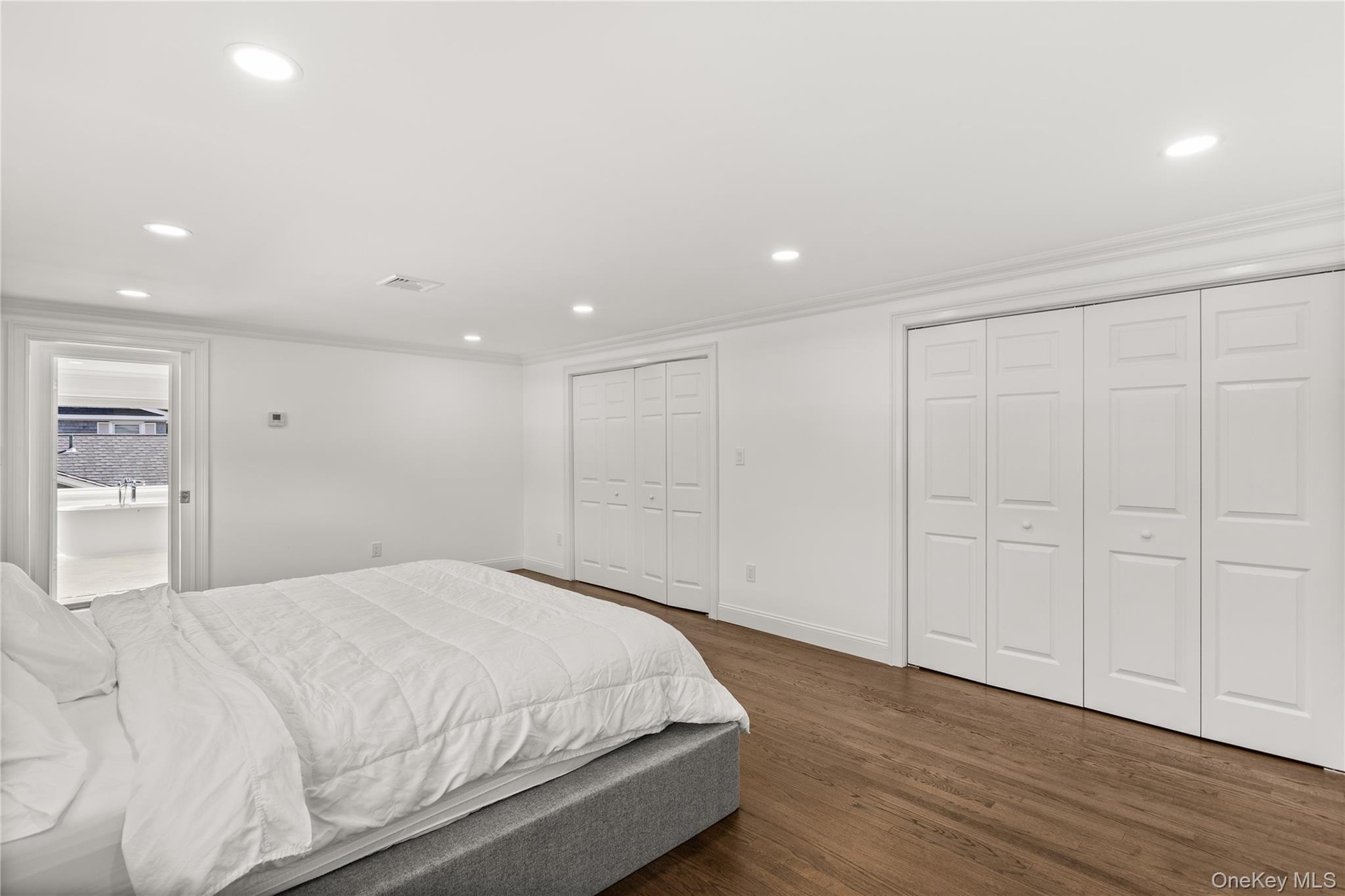Bedroom with recessed lighting, dark wood-style floors, two closets, and crown molding