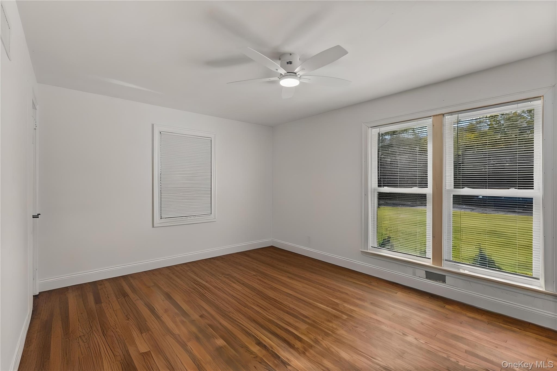 Empty room featuring dark wood-type flooring and ceiling fan