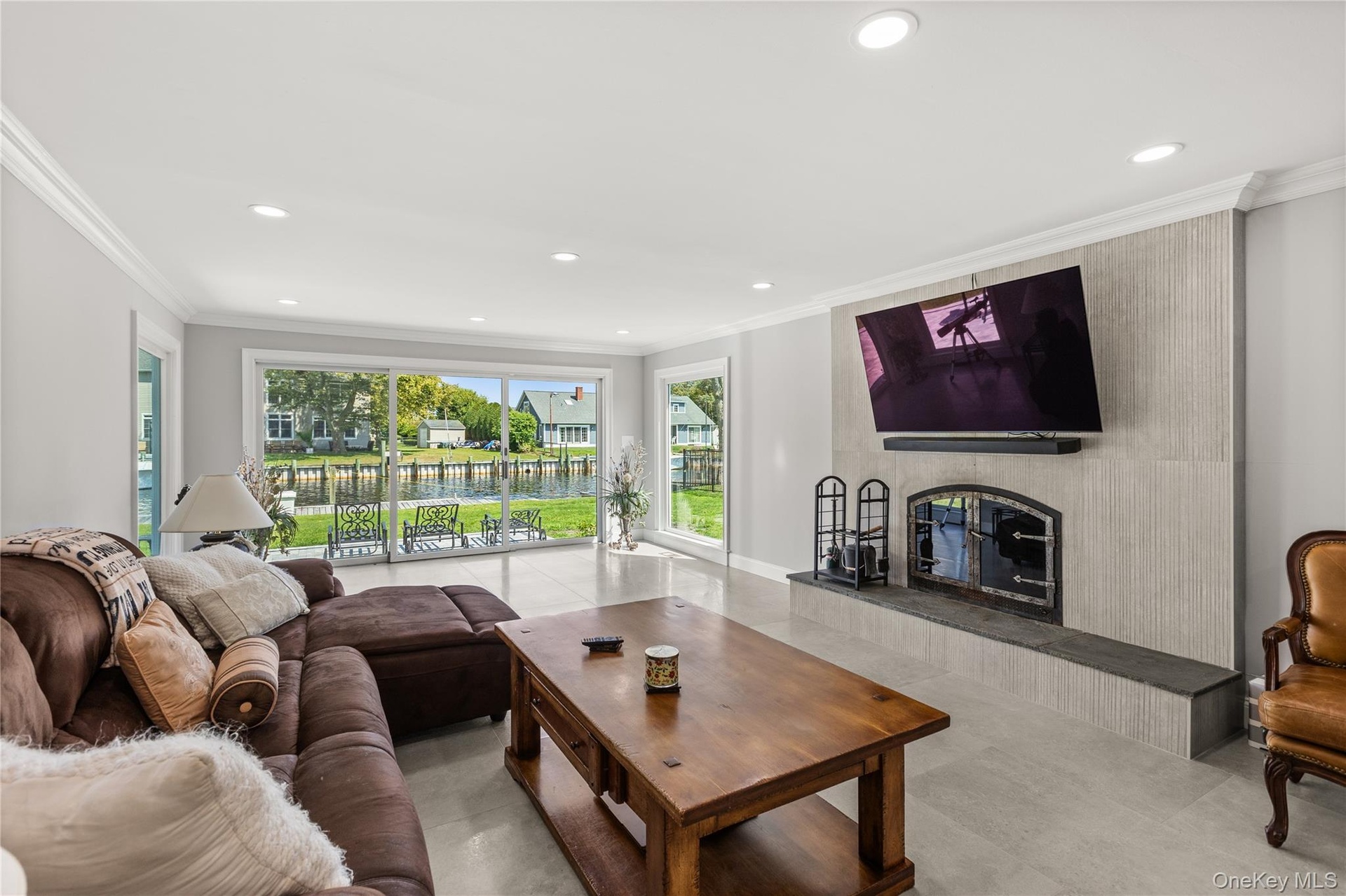 Living room with ornamental molding, recessed lighting, and a fireplace